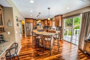 A kitchen island with barstools and wood kitchen flooring